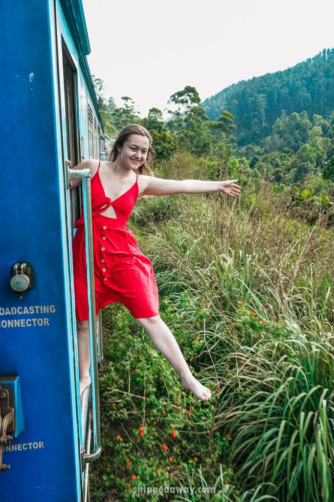 Girl in red dress hanging from the train in Sri Lanka