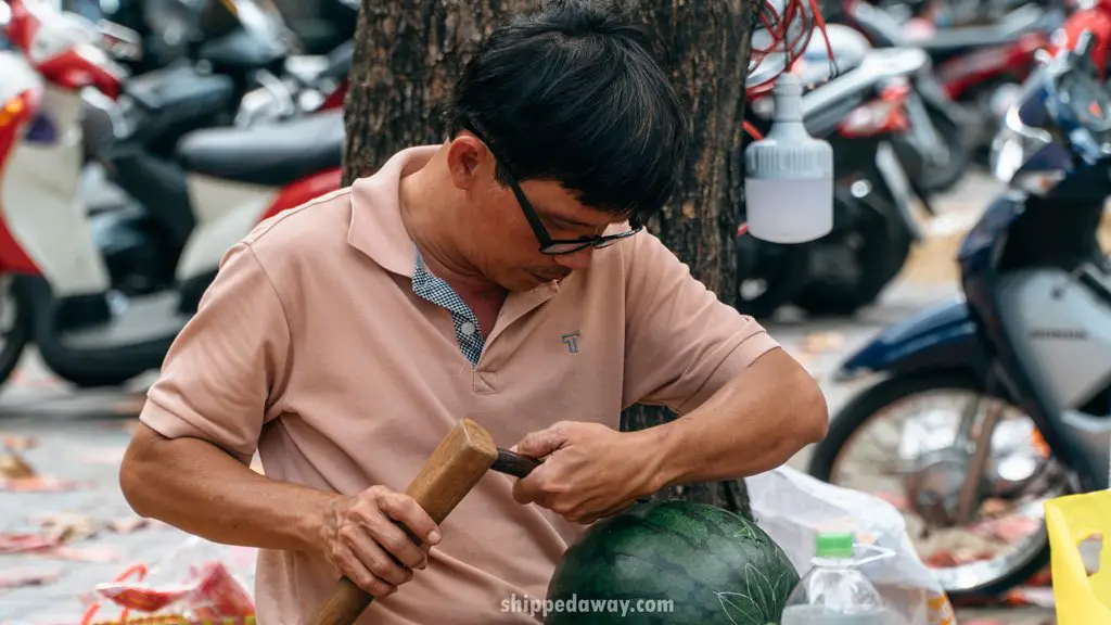 Man on the street carving a watermelon for Tet, Vietnamese New Year